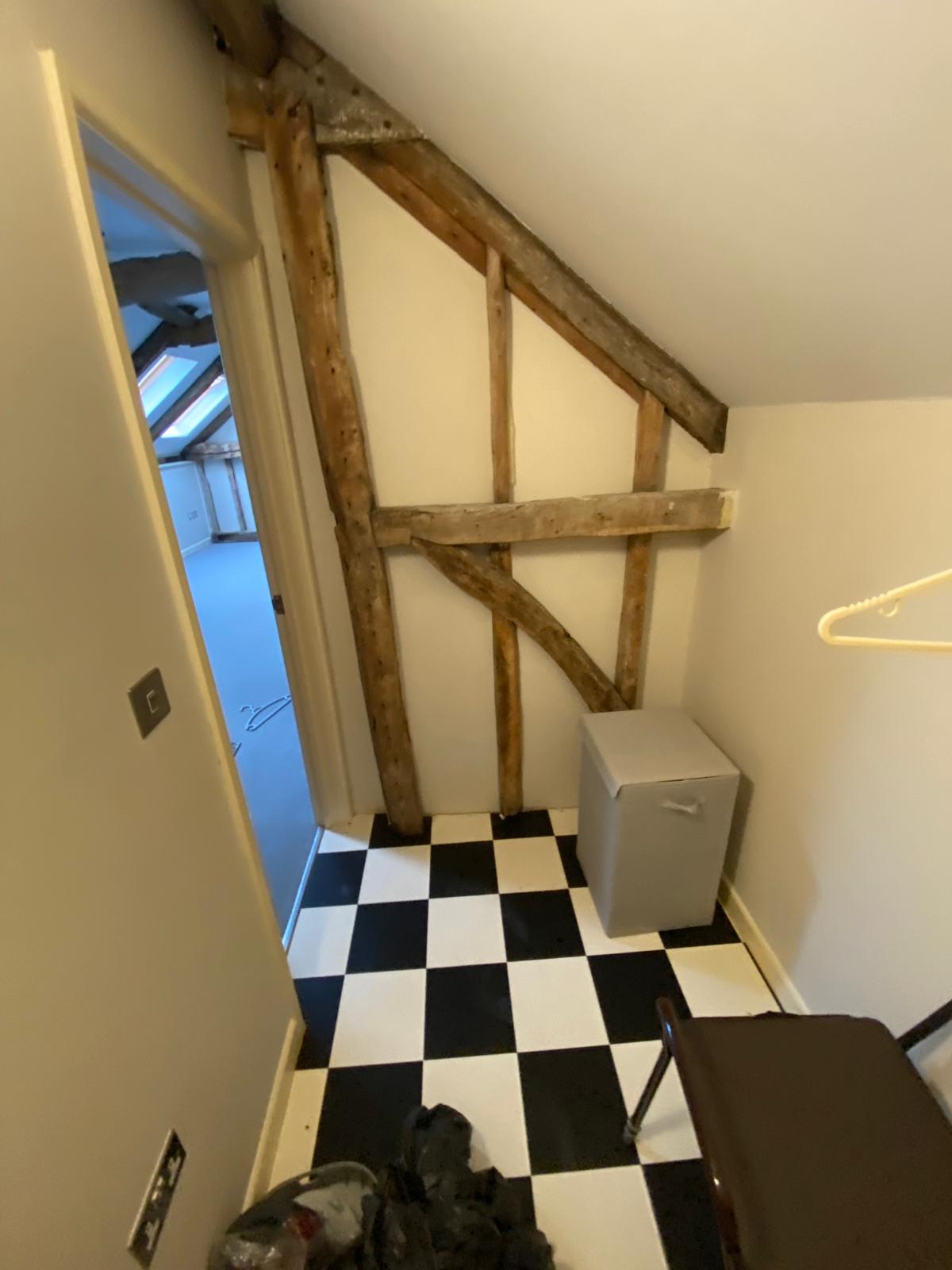 Loft conversion — before, unused loft space with exposed beams and checkerboard flooring